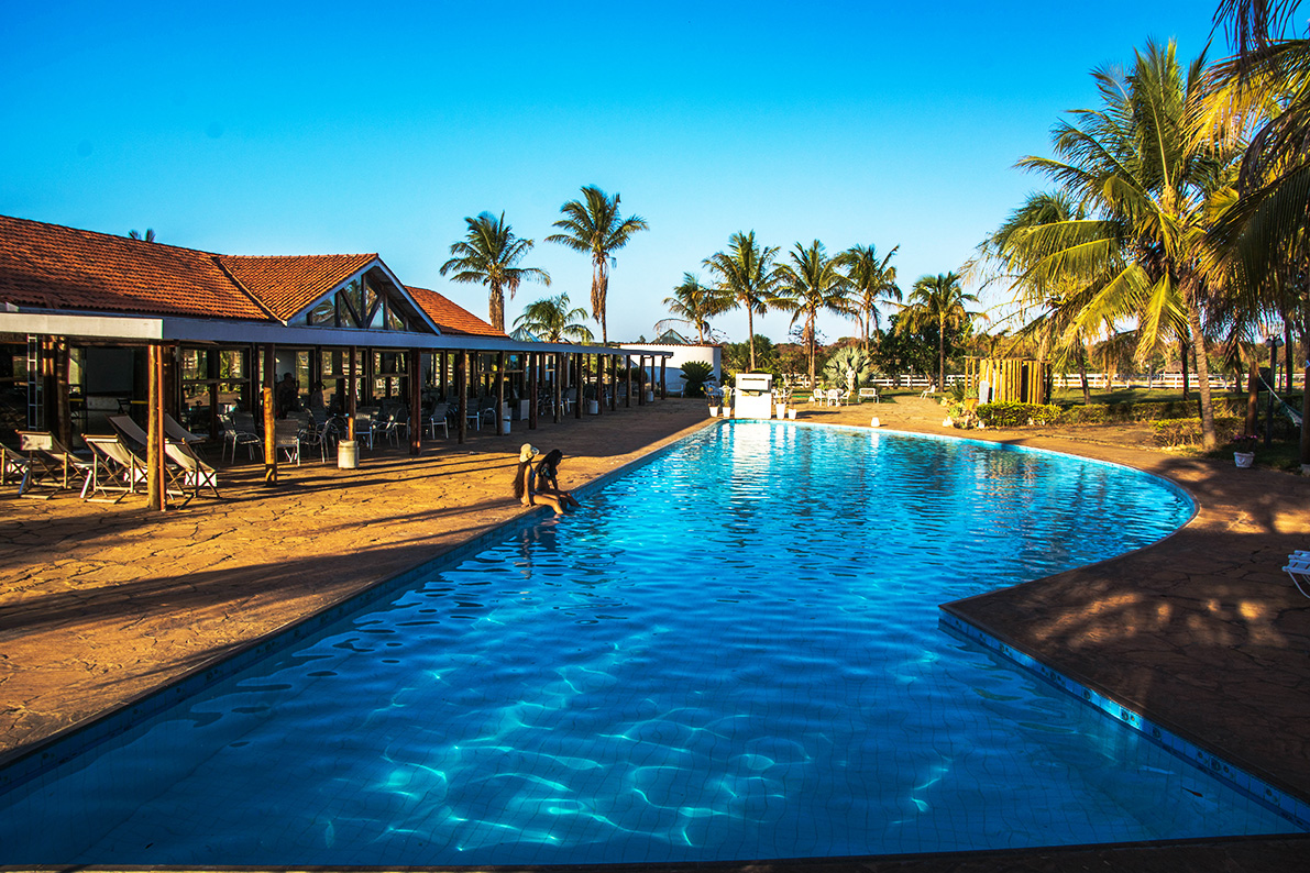 Piscina comprida do Hotel Mar Doce, com deck, restaurante e palmeiras ao fundo