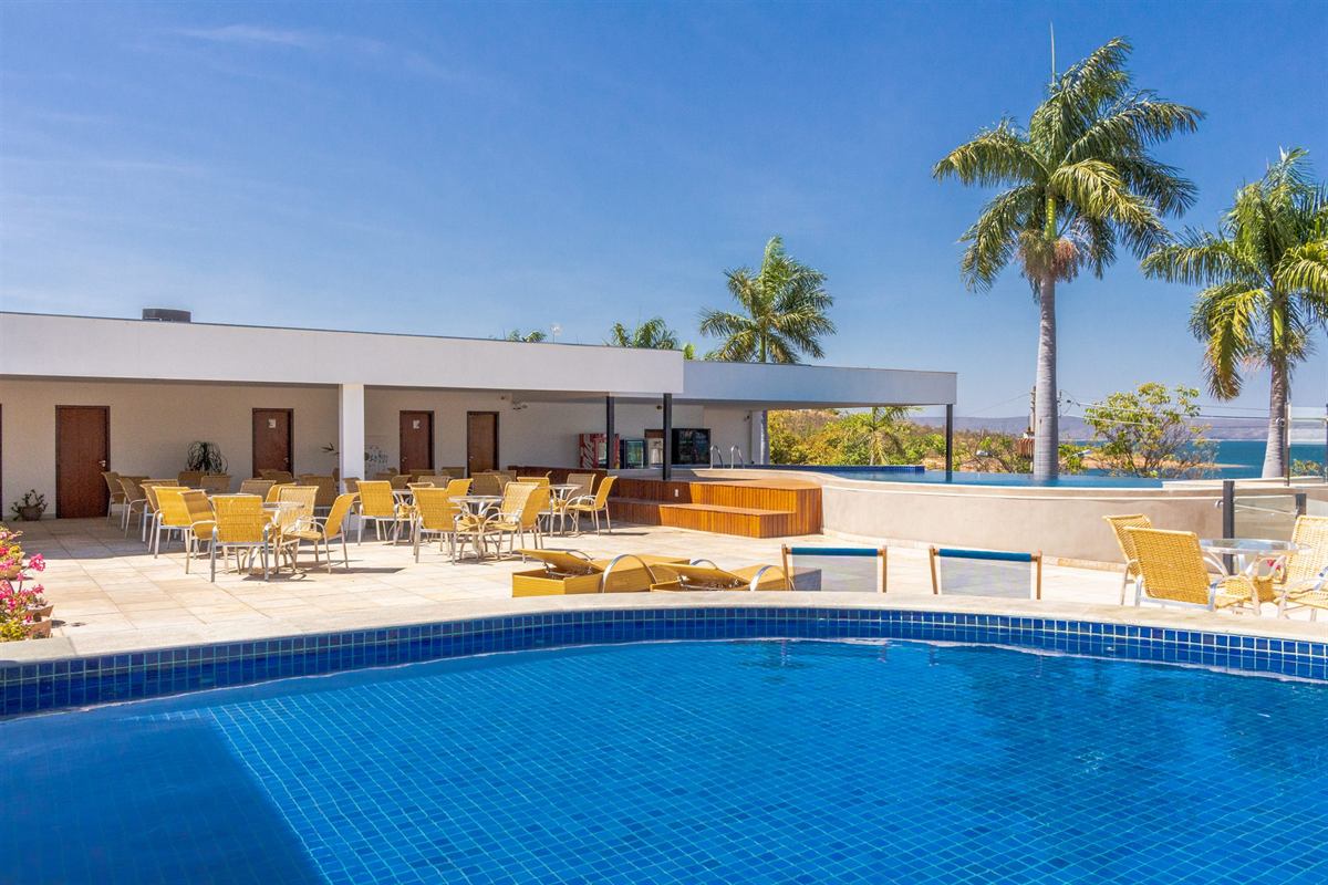 Piscina e área de lazer do Hotel Grande Lago, com cadeiras e palmeiras