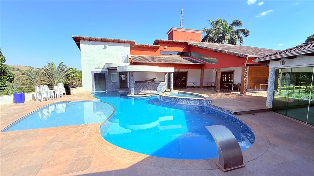 Piscina de fibra de formato orgânico com cascata e casa ao fundo