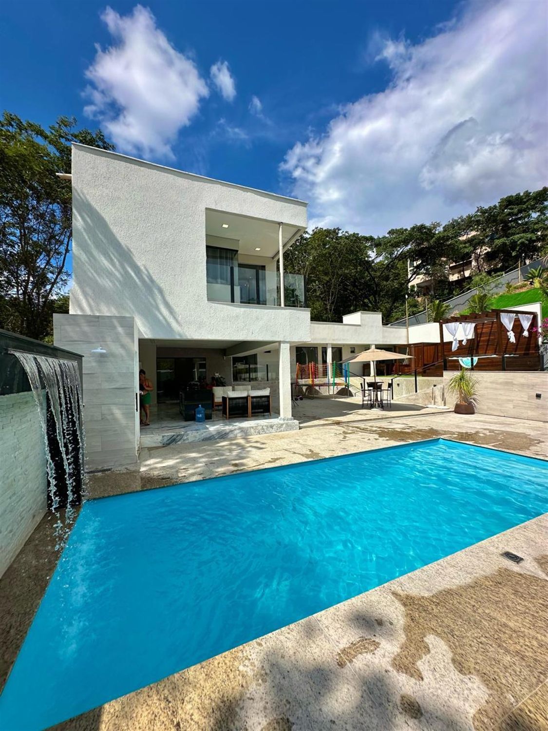 Piscina de fibra com cascata em frente a uma casa moderna de dois andares
