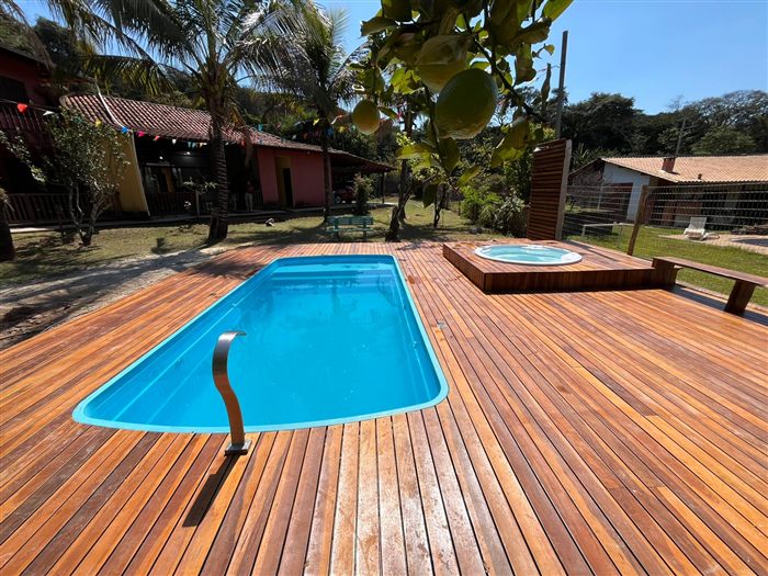 Piscina de fibra azul cercada por deck de madeira, com spa ao fundo