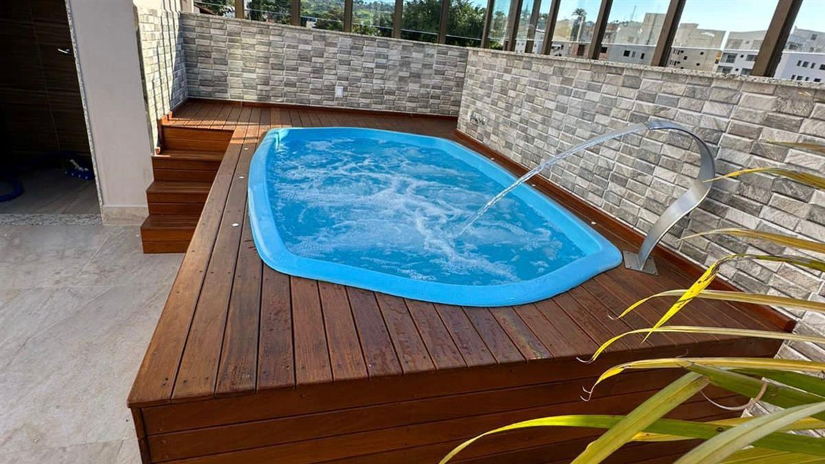 Piscina de fibra com hidromassagem, deck de madeira e cascata em aço